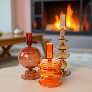 Set van 3 glaskandelaren van fijn glas in verschillende hoogtes en modellen in de kleuren maroon taupe en oranje in sfeervolle kamer met openbaar - WinQ