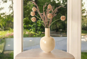 metalen vaas emaille beige 26x40cm met losse takken kunstbloemen op een tafel voor het raam - WinQ