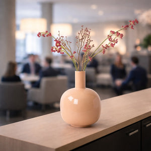 Vaas dark beige op balie in hotel lobby met rode kunstbloemen - WinQ