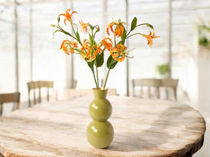 Gloriosa in een groene vaas op een houten tafel _ WinQ