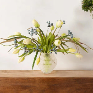 kunstbloemen boeket met witte tulpen met groen blad en takken met zwarte bessen op een glasvaas op een bruine houten tafel - WinQ