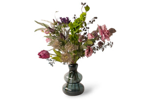 Boket zijden bloemen op een blauwe glas vaas in een arrangement in de kleuren paars, lila en grijs